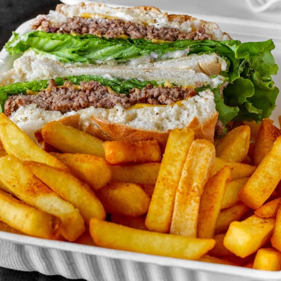 Liberty Pizza & Sub's steak and cheese sub with lettuce and fries in a takeout container.