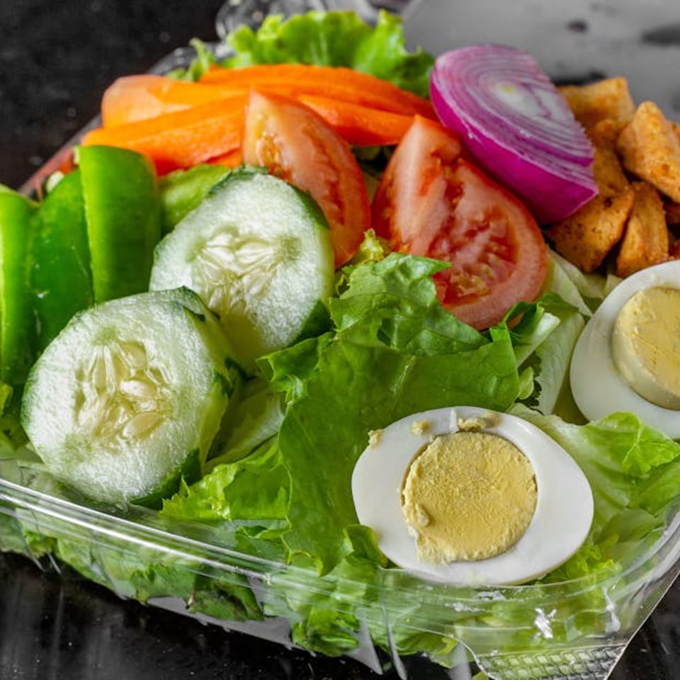 Fresh garden salad with lettuce, cucumbers, tomatoes, carrots, red onion, croutons, and hard-boiled eggs.